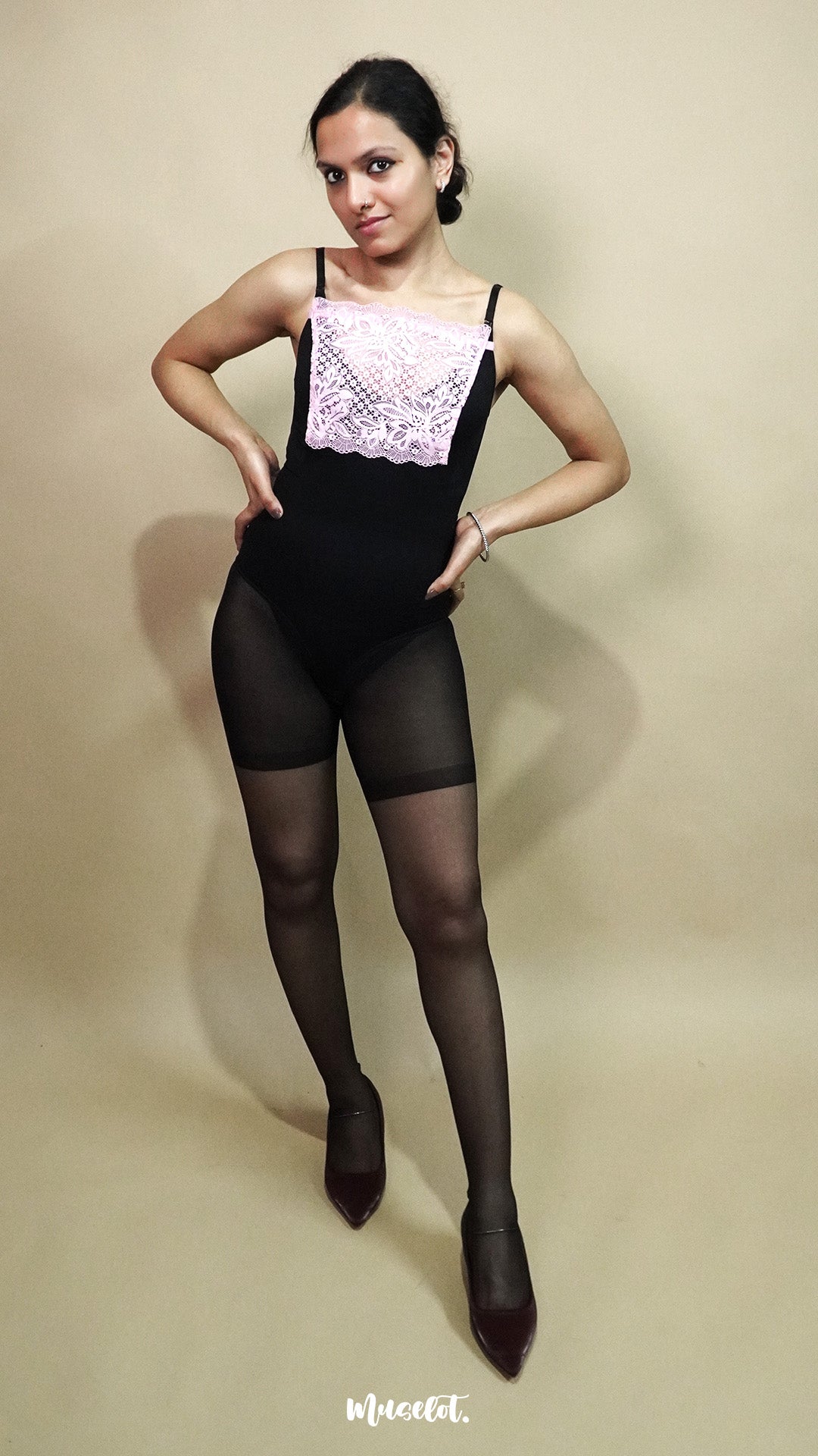 full body view of woman wearing baby pink lace camisole insert over black dress on beige background, showcasing neat neckline coverage with wide lace mock camisole for deep neck outfits – muselot