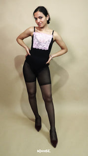 full body view of woman wearing baby pink lace camisole insert over black dress on beige background, showcasing neat neckline coverage with wide lace mock camisole for deep neck outfits – muselot