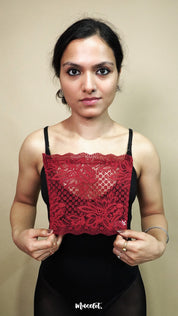 front view of woman holding maroon lace camisole insert to show width and neckline coverage on beige background, highlighting lace mock camisole styling for deep neck outfits – muselot