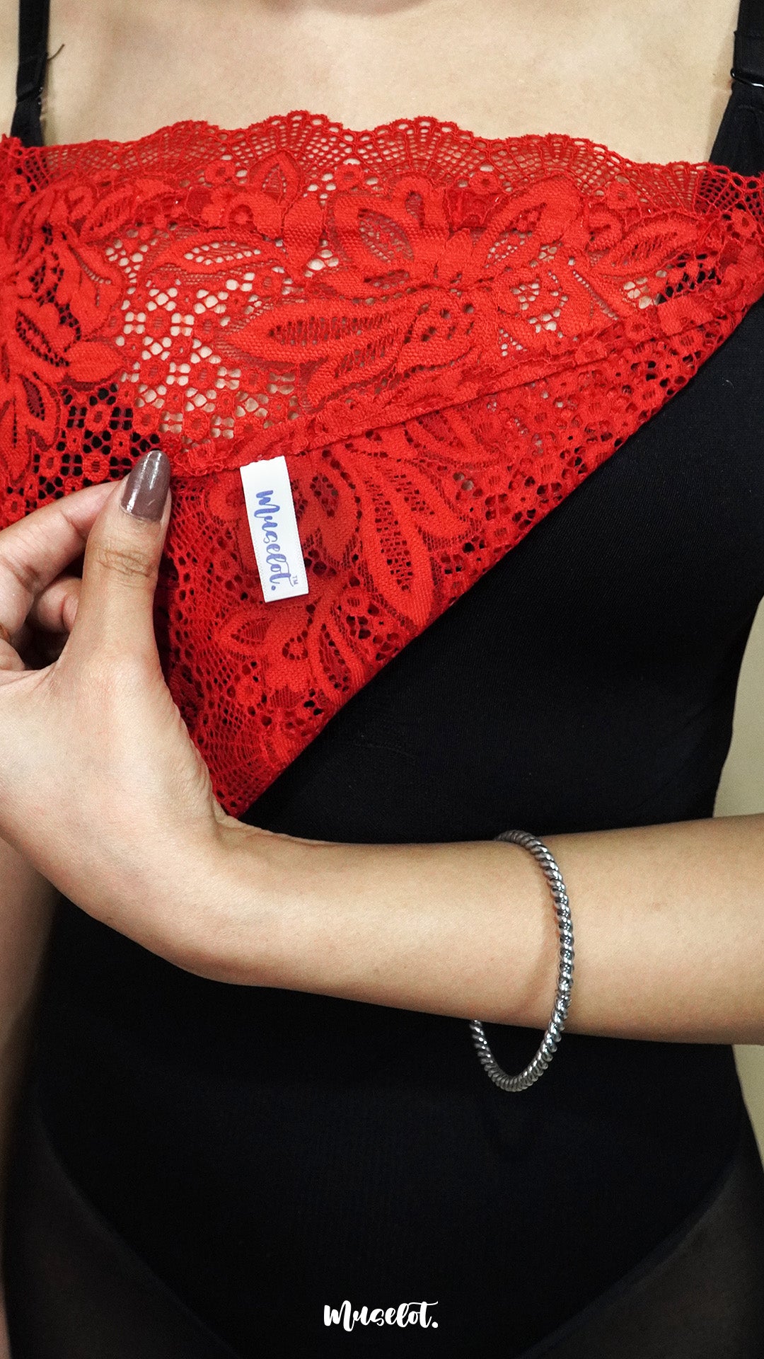close up of red lace camisole insert being held to show muselot tag and lace fabric, highlighting premium floral lace and neckline coverage for deep neck dresses – muselot