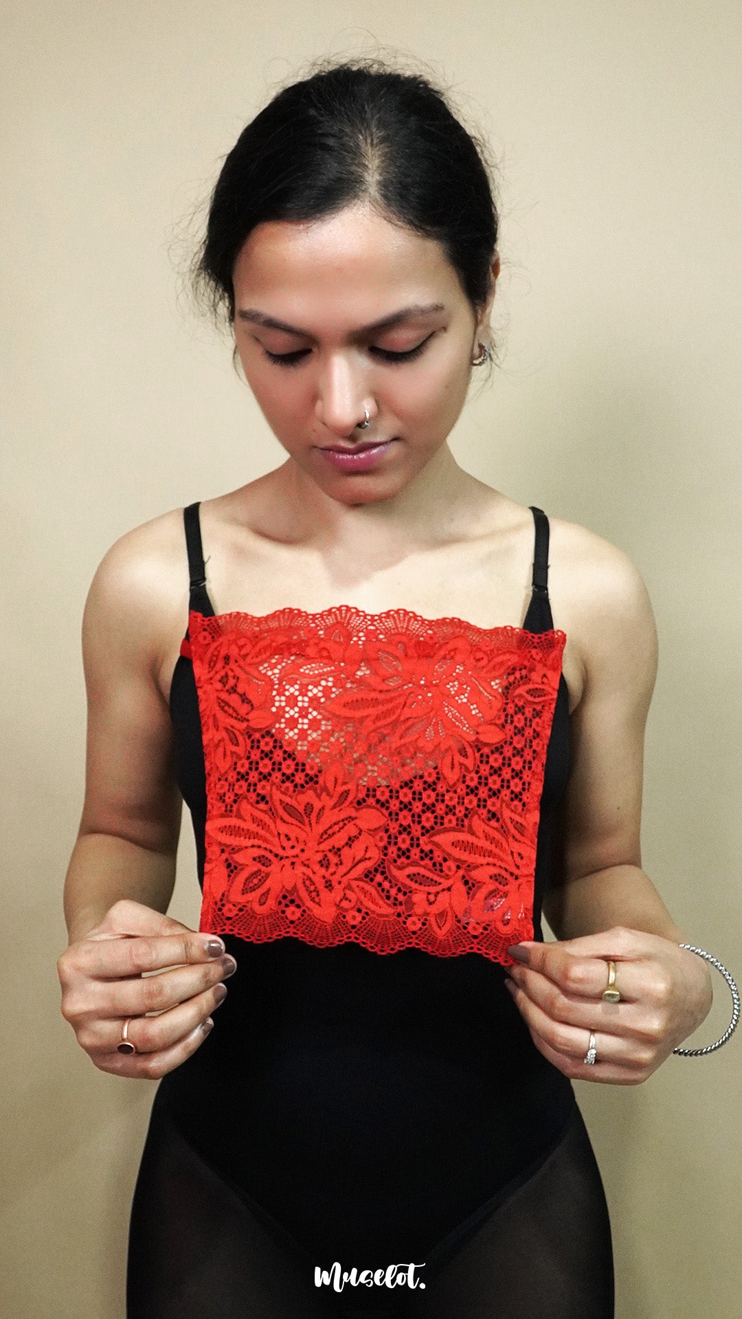 front view of woman holding red lace camisole insert to show width and coverage on beige background, highlighting lace mock camisole styling for deep neck tops – muselot