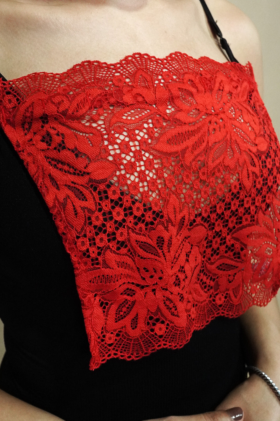 side close up of woman wearing red lace camisole insert over black top on beige background, highlighting wide lace design for better coverage on low neckline outfits – muselot