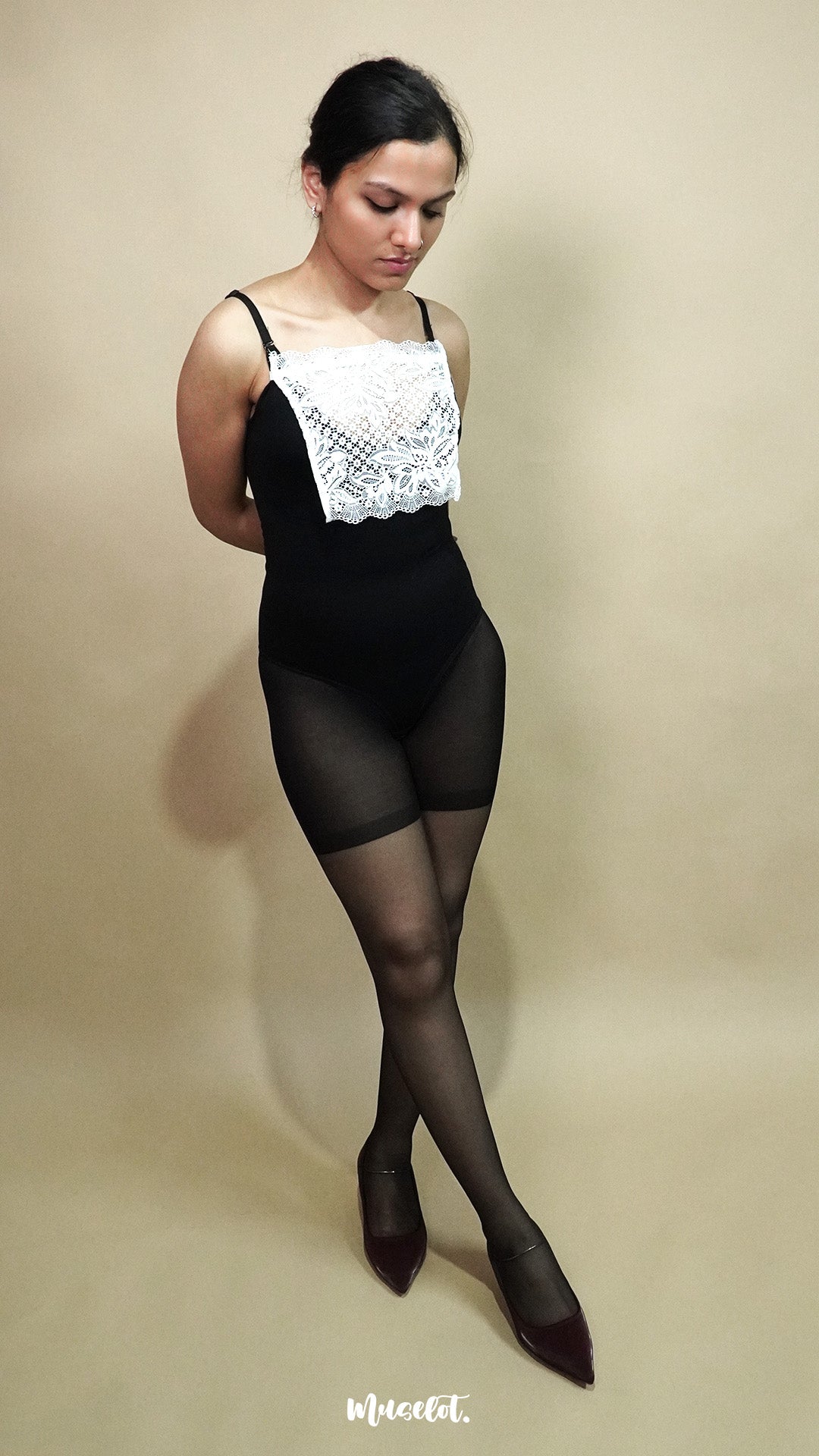 full length pose of woman wearing white lace camisole insert over black bodysuit on beige background, showing how mock lace panel adds neat coverage to deep neckline – muselot