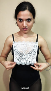 front view of woman holding white lace camisole insert to display full width and shape, showing mock lace layer used for covering deep neck tops neatly – muselot