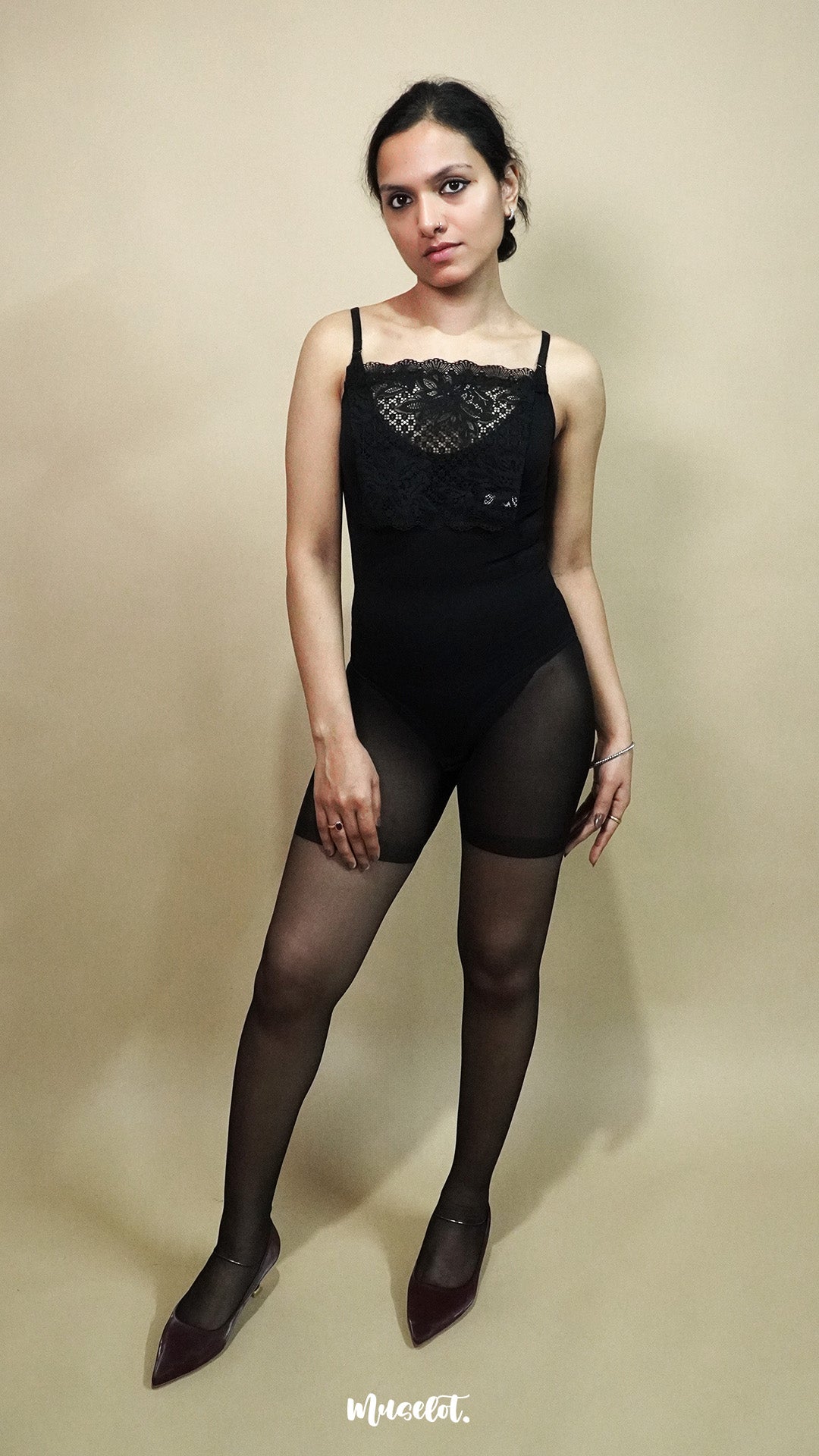 full body view of woman wearing black lace camisole insert over black outfit on beige background, showcasing elegant deep neckline styling with sheer floral lace mock camisole for layered look – muselot