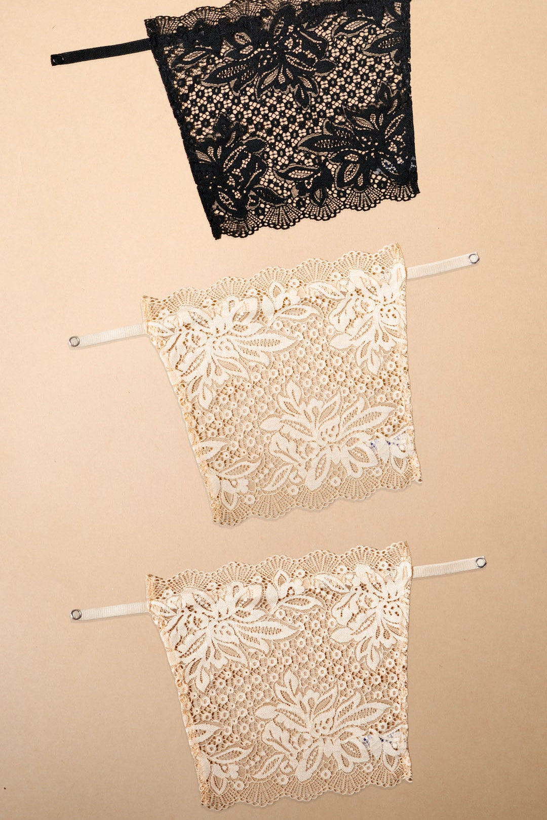 Three lace clip-on neckline covers in black and beige tones displayed on a beige background, featuring premium floral lace detailing, adjustable straps and versatile styling options. Designed for deep neck tops, kurtis, dresses and blouses, these lightweight mock camisole inserts provide elegant neckline coverage while blending naturally with a wide range of outfits and skin tones – Muselot
