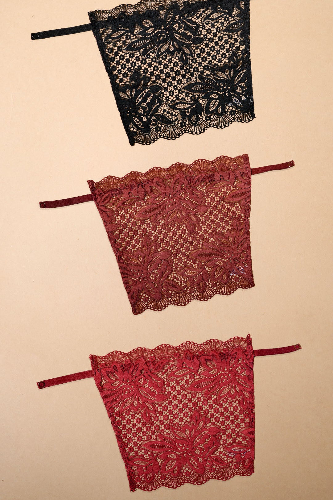 Three floral lace clip-on camisole inserts in black, burgundy and maroon displayed on a beige background, showcasing elegant neckline coverage, intricate lace detailing and versatile styling for deep neck tops, dresses, blouses and modest layering looks – Muselot