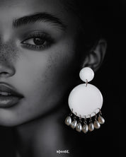 Close-up of a woman wearing designer stud drop earrings, featuring smooth white circular tops with delicate pearl drops, highlighting the graceful fusion of simplicity and elegance — Muselot.