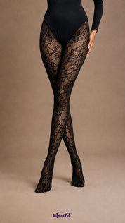 A product-focused view of crossed legs in Dusk Bloom black patterned stockings showing oversized floral lace motifs and semi-sheer mesh detailing - Muselot