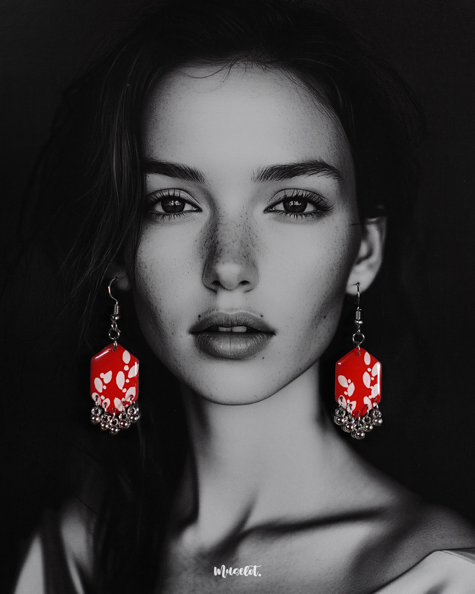 A model wearing the Mehar floral red hook earrings showcases the striking handcrafted design — vivid red hexagonal drops with delicate white floral motifs and metallic ghungroo accents, highlighting the bold contrast and showcasing a modern yet traditional fusion — Muselot.