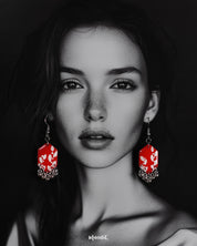 A model wearing the Mehar floral red hook earrings showcases the striking handcrafted design — vivid red hexagonal drops with delicate white floral motifs and metallic ghungroo accents, highlighting the bold contrast and showcasing a modern yet traditional fusion — Muselot.