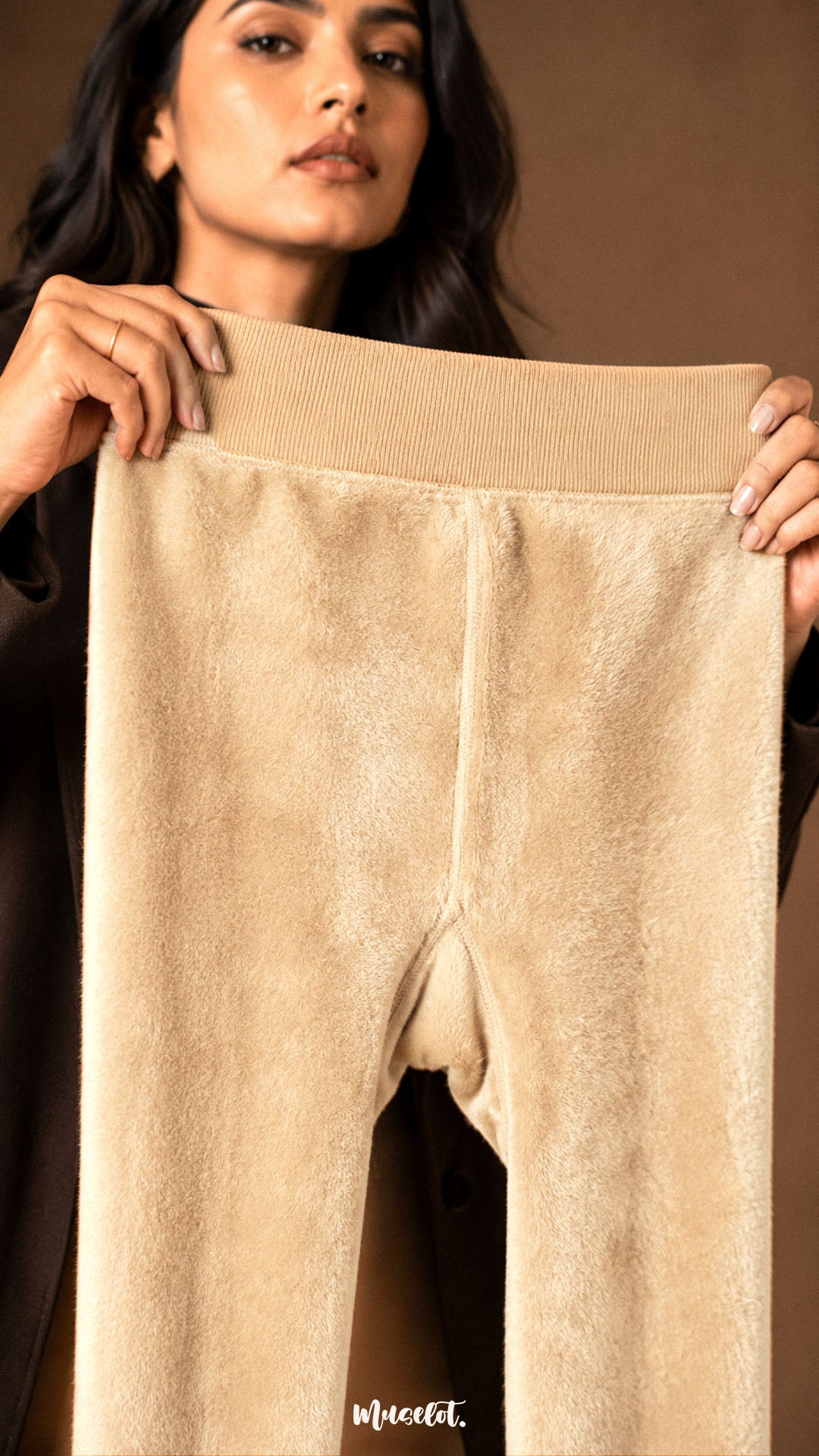 A woman holding beige winter stockings open to show the dense soft fleece lining, wide waistband and warm fur interior - Muselot