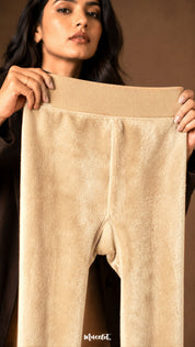 A woman holding beige winter stockings open to show the dense soft fleece lining, wide waistband and warm fur interior - Muselot