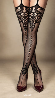 A woman standing with her legs crossed wearing black fishnet garter-style stockings, showcasing the symmetrical lace motif at the top, the vertical decorative pattern running down the legs and the elegant styling with pointed burgundy heels - Muselot