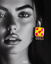 Model wearing handmade earrings, highlighting the yellow hand-painted stud with pink-red accents and dangling silver ghungroo detail – Muselot.
