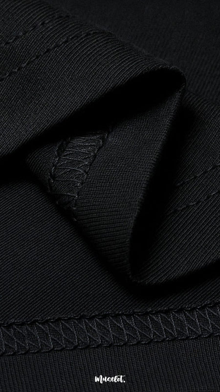 A zoomed-in view of the unisex oversized black t-shirt, highlighting the double seam stitching for added strength, lasting durability, and a neat polished finish—Muselot