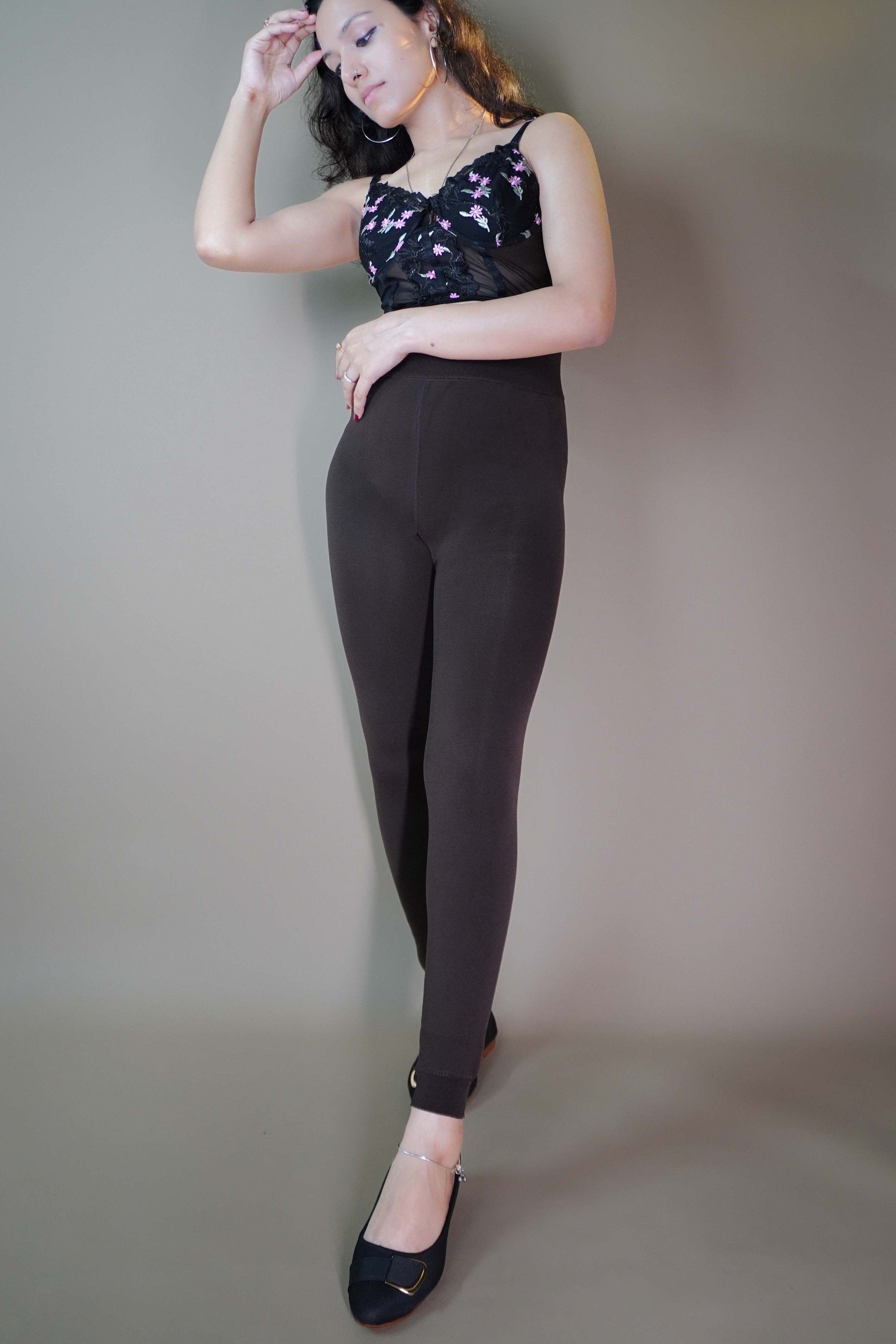 A model, wearing open-feet brown warm tights, is highlighting their cozy, snug fit while showcasing the open-foot design. The rich brown color adds a stylish touch, perfect for pairing with footwear while keeping warm during colder days. -Muselot