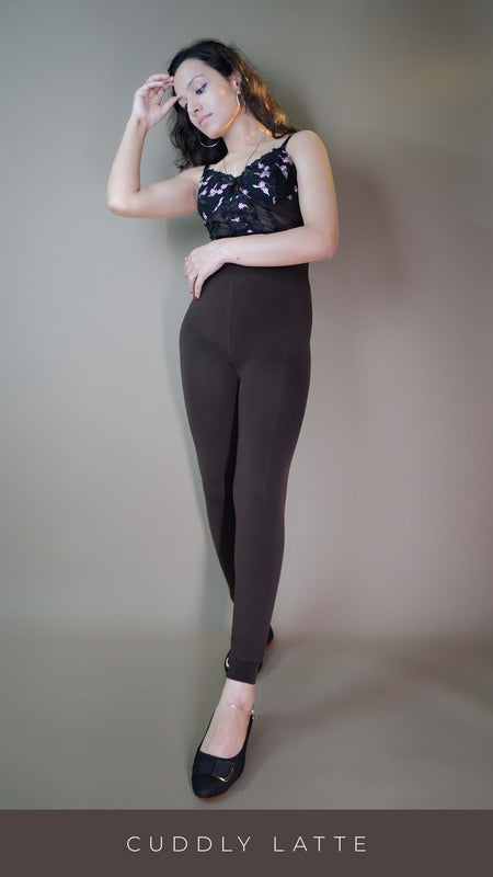 A model, wearing open-feet brown warm tights, is highlighting their cozy, snug fit while showcasing the open-foot design. The rich brown color adds a stylish touch, perfect for pairing with footwear while keeping warm during colder days. -Muselot