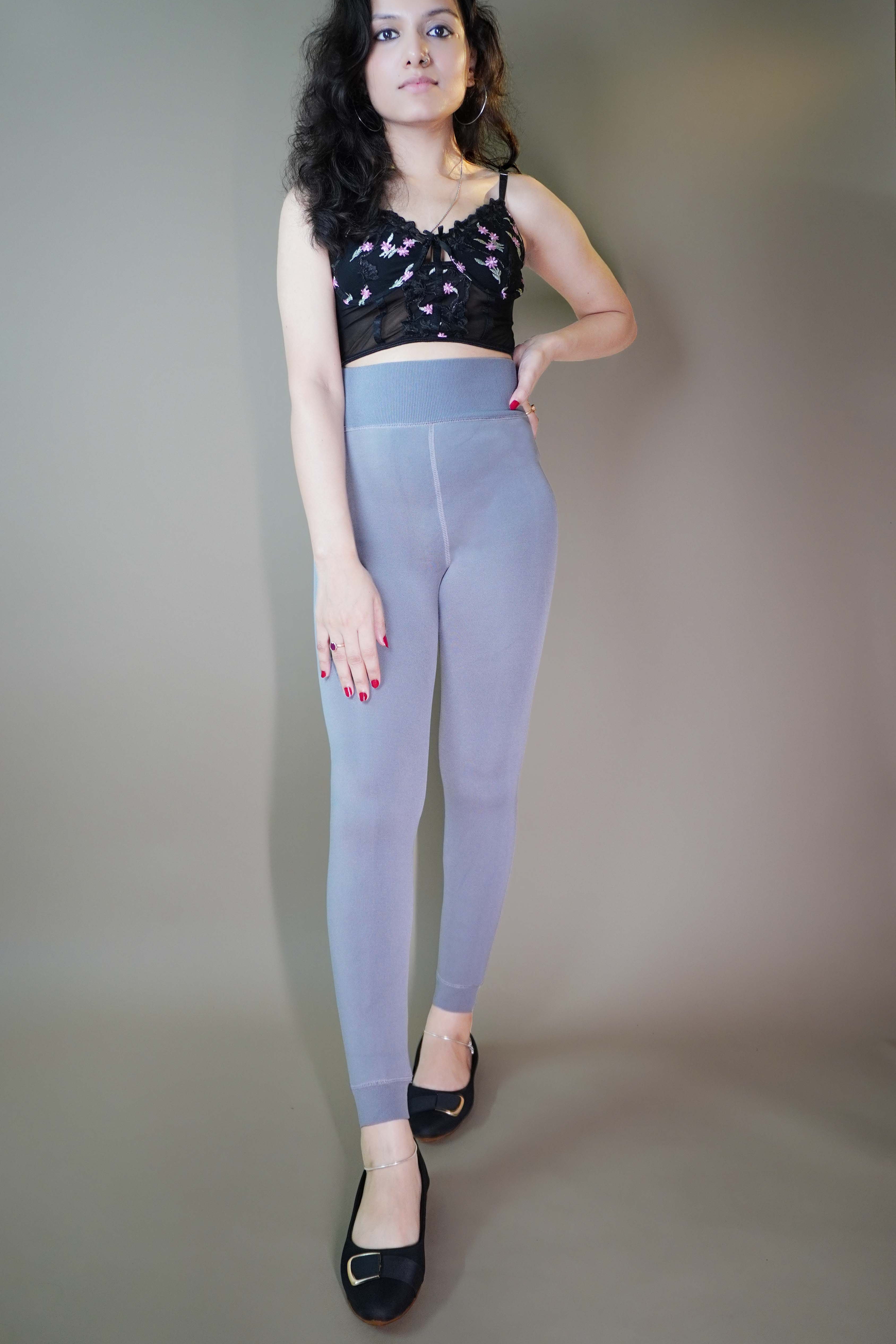 A model, wearing open-feet fur-lined grey tights, showcasing their plush, insulating lining while highlighting the open-foot design. The grey color adds a sleek, cozy touch, making these tights both stylish and practical for colder days. -Muselot