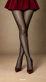 A close-up shot of a woman’s crossed legs in black sheer-effect polka dot stockings, highlighting the delicate dot pattern, smooth translucent appearance and refined full-leg finish - Muselot
