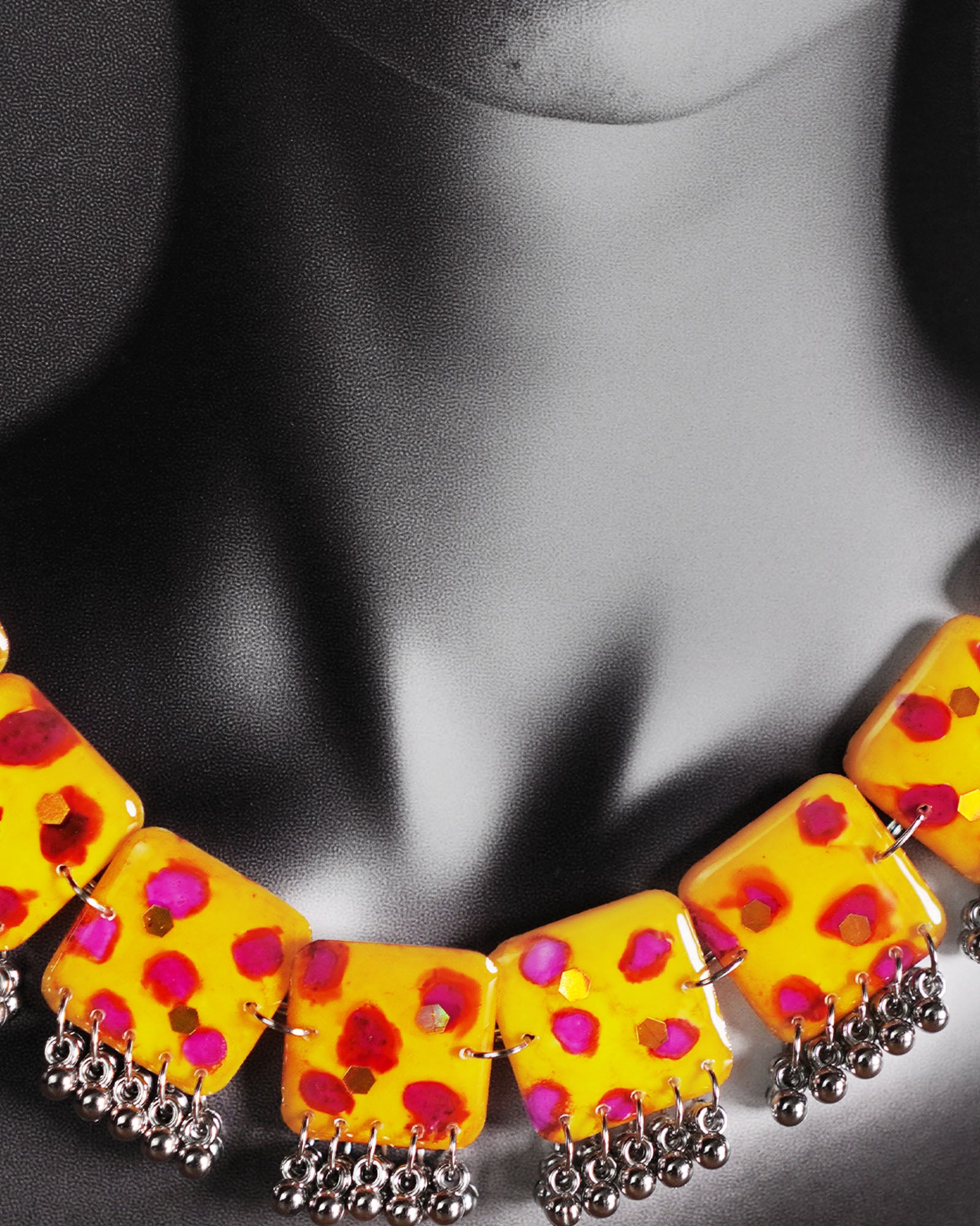 Model wearing yellow handmade jewelry set, featuring hand-painted square necklace tiles with pink-red accents and silver ghungroo detailing, styled to highlight the neckline – Muselot.